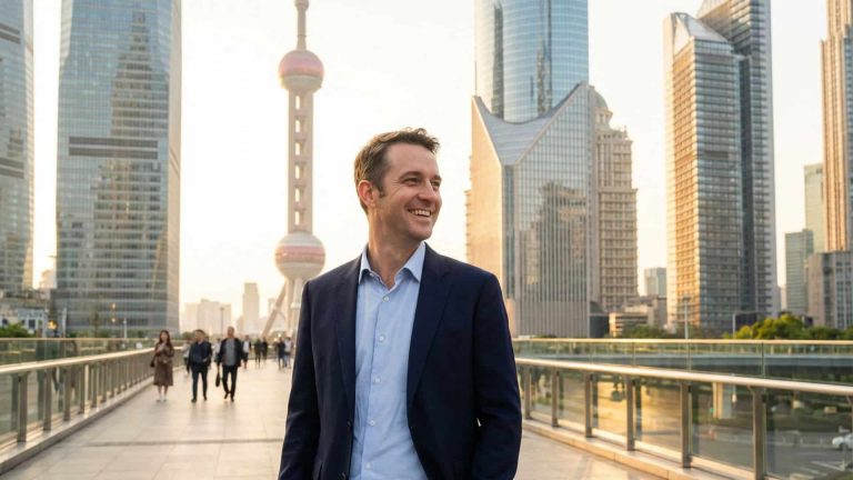 A person wearing a navy blazer, light blue shirt, and beige trousers stands on a pedestrian walkway in a modern cityscape with tall glass skyscrapers. The iconic Oriental Pearl Tower is visible in the background, and the scene is bathed in warm golden-hour sunlight. Several people are walking further down the walkway, and the overall setting conveys an urban, professional, and vibrant atmosphere.